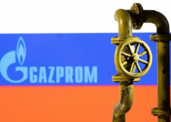 Il logo Gazprom impresso su una bandiera russa davanti a una miniatura di un gasdotto . REUTERS/Dado Ruvic/